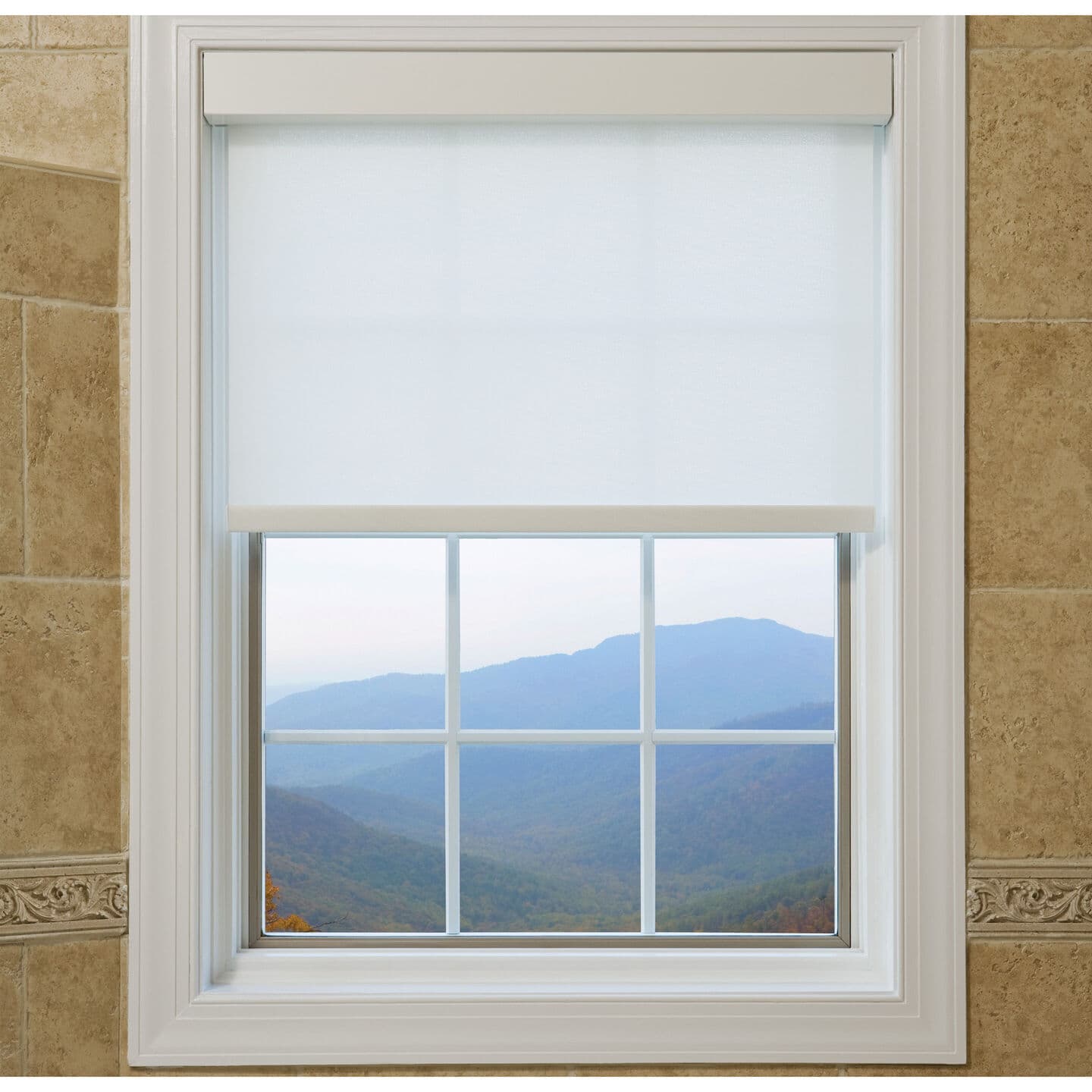 White Lutron Sivoia QS roller shade lowered halfway over a divided-light window framing a hazy blue mountain view