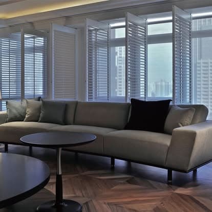 Sarasota living room comparing white plantation shutters with soft roller shades on adjacent windows