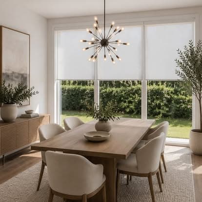 White roller shade lowered over a large sliding glass door in a bright modern dining room