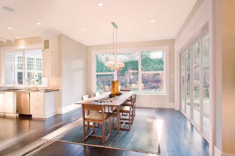 Bright dining area with large white-framed PGT Sparta aluminum picture and single-hung windows and a sliding glass door opening to the backyard