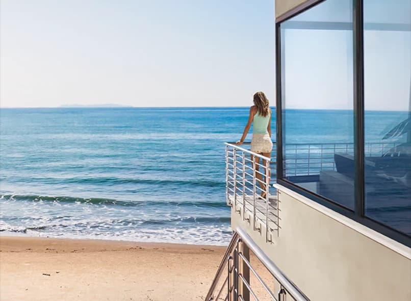 Impact-rated windows and doors framing an oceanfront balcony view on a coastal Florida home