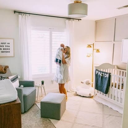 A parent holding a baby in a nursery with cord-free window coverings.