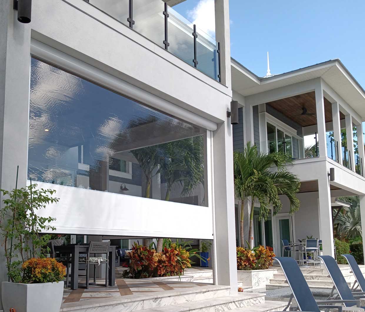 Fenetex OneTrack clear vinyl panels enclosing a two-story waterfront patio beside a pool.