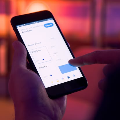 Hand holding a phone running the Lutron app, adjusting a “Curtain 1” zone with a slider