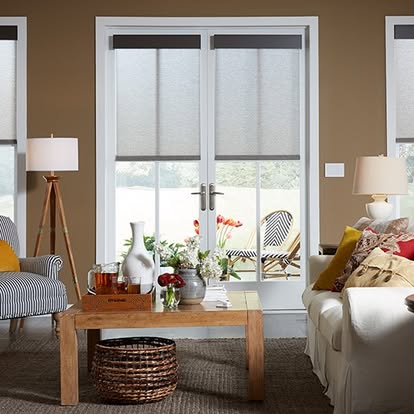 Cellular honeycomb shades half-lowered on French doors and side windows in a cozy tan living room