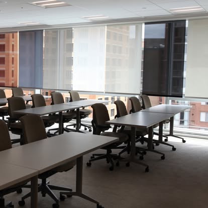 Corporate conference and training room with solar shades lowered across a wall of city-view windows