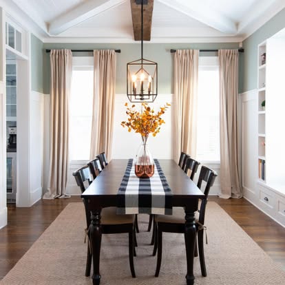 Cream pinch-pleat drapery panels flanking dining room windows above plantation shutters