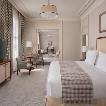 Elegant classic hotel bedroom with patterned green drapery and a plaid bed throw