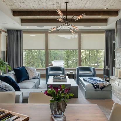 Motorized shades and drapery aligned across a wall of glass in a mountain-view great room