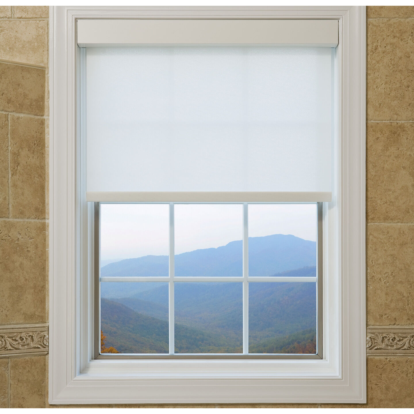 White Lutron Sivoia QS roller shade lowered halfway over a divided-light window framing a hazy blue mountain view