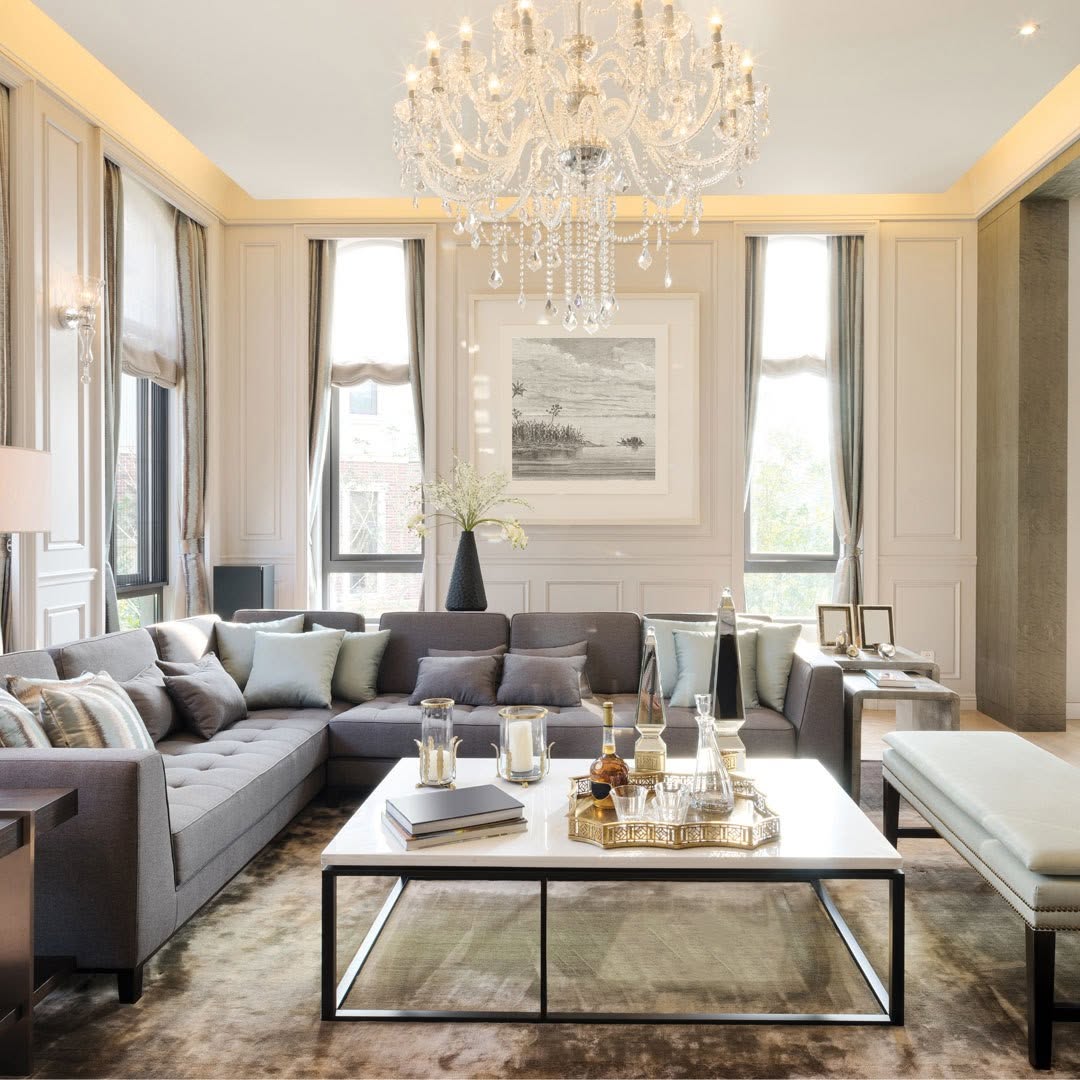 Elegant traditional living room with Roman shades and drapery panels on tall windows beneath a crystal chandelier