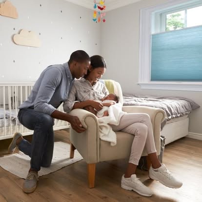 Blue cellular honeycomb shade on a nursery window as a family cradles their newborn nearby