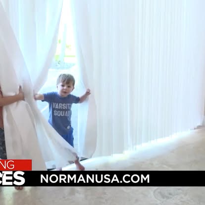 NormanUSA.com video still of a child playing among floor-to-ceiling sheer draperies