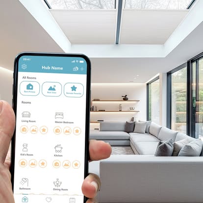 A smartphone running a smart-home app controlling motorized shades in a bright modern living room