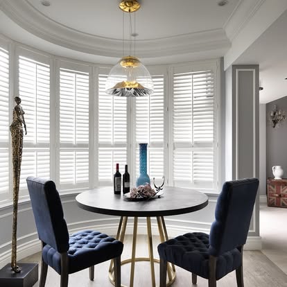 Norman plantation shutters wrapping a curved bay window around a round dining table.