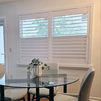 White plantation shutters with an open top tilt over a breakfast nook with a round glass table