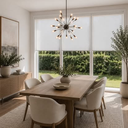 White roller shade lowered over a large sliding glass door in a bright modern dining room