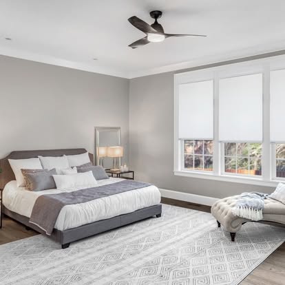 White roller shades on two windows in a serene gray primary bedroom