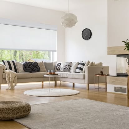 White roller shade half-lowered over a large window in a warm beige living room with a sectional sofa