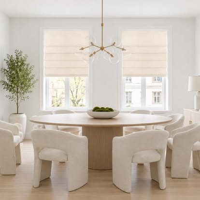 Soft cream Roman shades on bay windows in an airy neutral dining room
