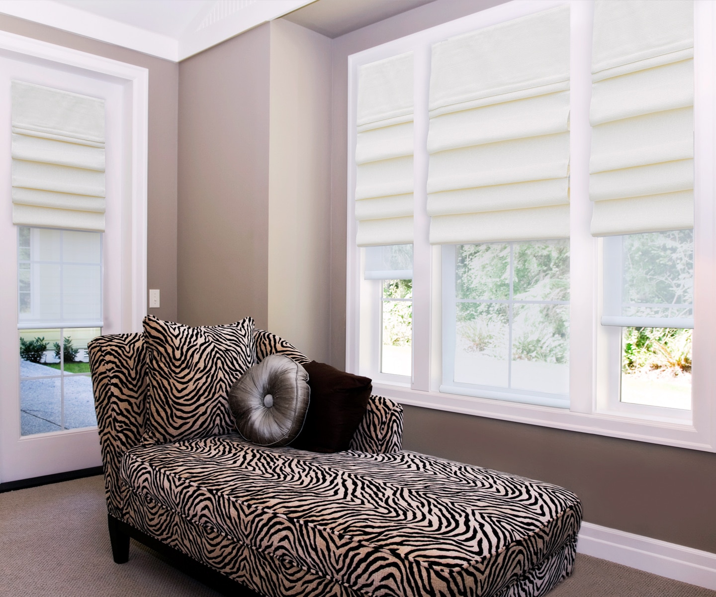 Flat cream Roman shades over three windows and a door in a warm taupe sitting room