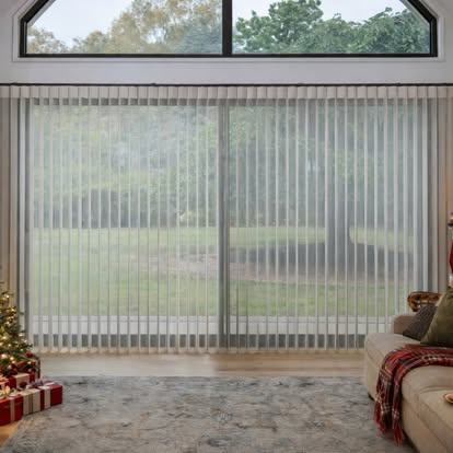 Floor-to-ceiling vertical sheer shades across a wide window in a cozy living room decorated for the holidays