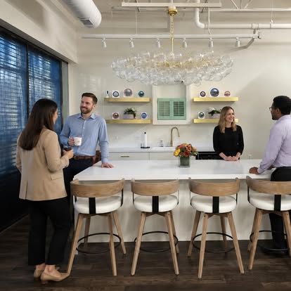 Team members talking in a bright modern office kitchen with light-filtering shades