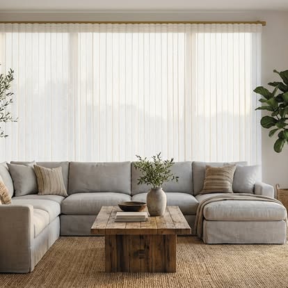 Vertical sheer shades behind a linen sectional in a warm, layered living room