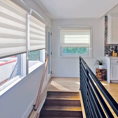 Transitional zebra shades on stairwell and landing windows in a bright modern home