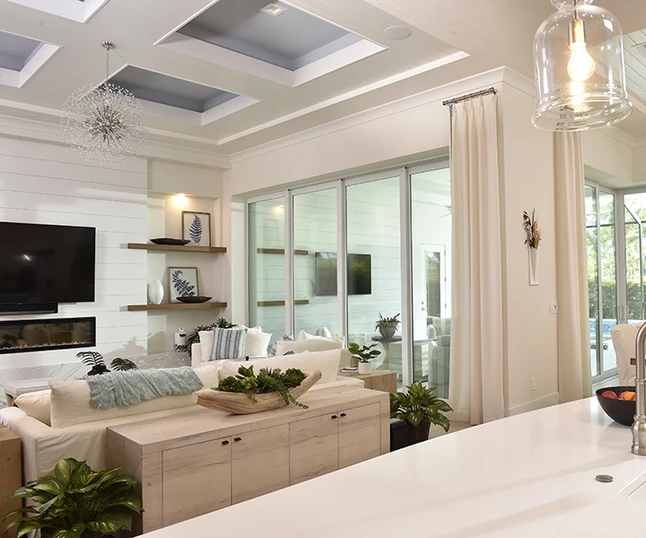 Bright coastal living room with large white-framed PGT sliding glass doors opening to a screened lanai