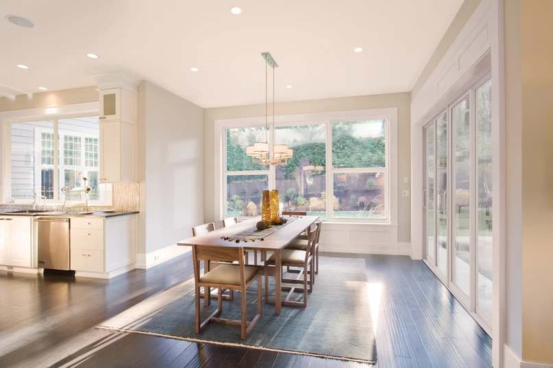 Bright dining area with large white-framed PGT Sparta aluminum picture and single-hung windows and a sliding glass door opening to the backyard