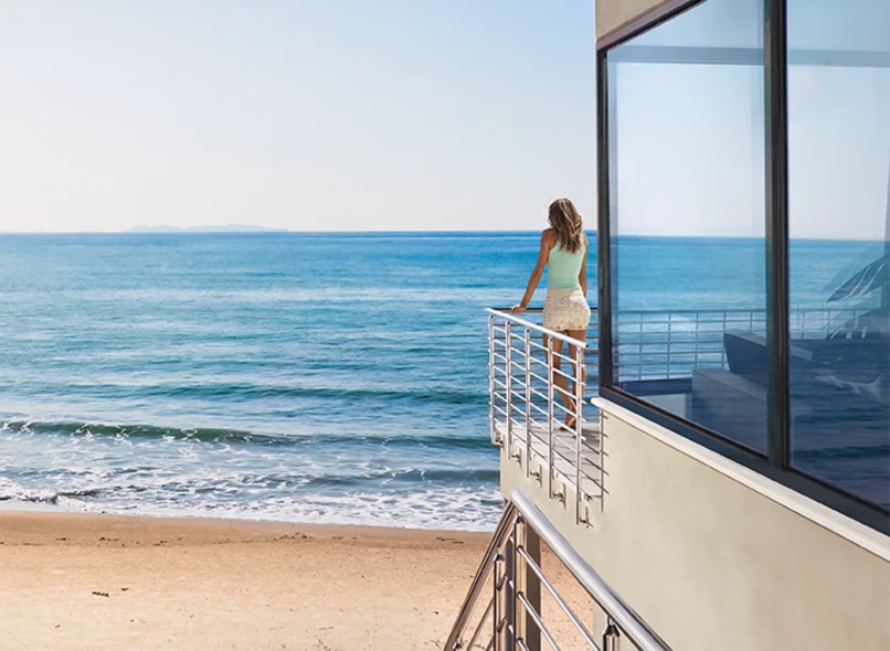 Impact-rated windows and doors framing an oceanfront balcony view on a coastal Florida home