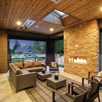 Covered outdoor living space with exterior screen shades and a stacked-stone fireplace