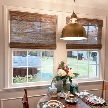 Breakfast nook with natural woven wood Roman shades on double-hung windows — product style example