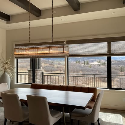 Natural woven wood shades on large windows framing a mountain view in a modern dining room