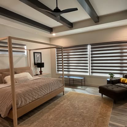Transitional zebra shades with alternating sheer and solid bands in a warm wood-beamed bedroom
